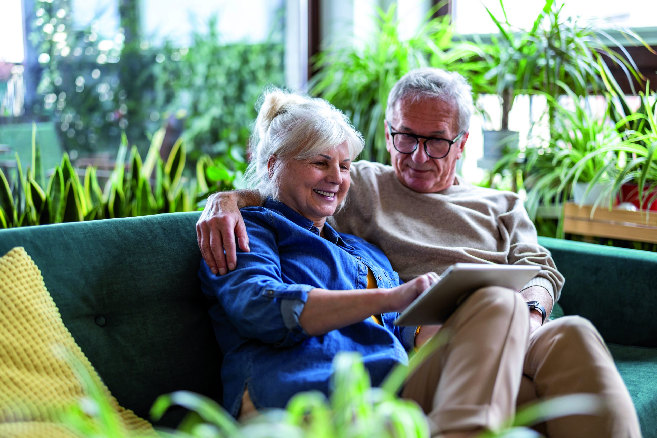 Happy,Senior,Couple,Using,Digital,Tablet,While,Sitting,On,Sofa
